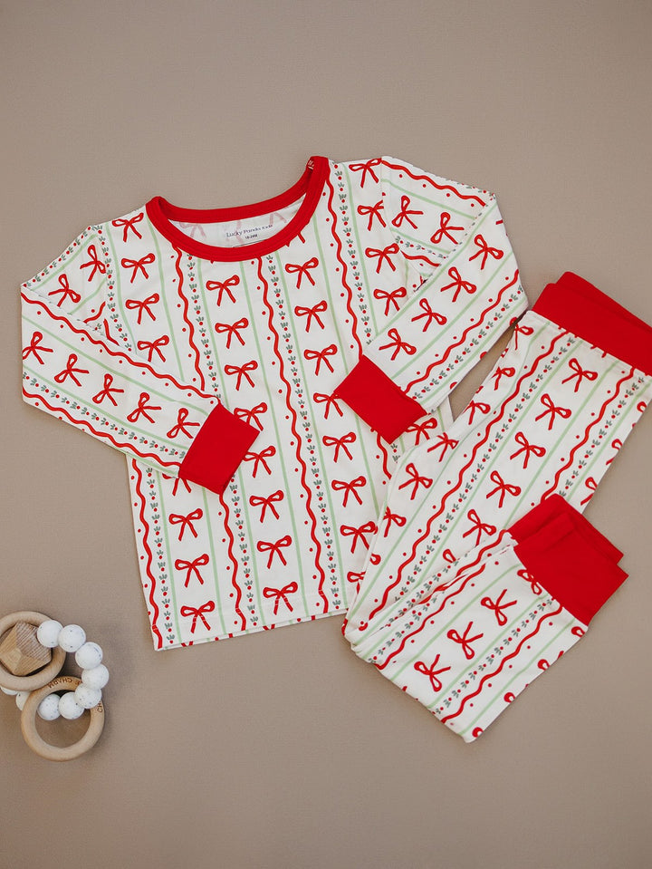 Christmas Bows pajama top and matching pants laid flat, showing rows of red bows and red trim.