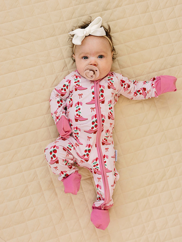 Baby in a pink floral onesie lying on a beige surface