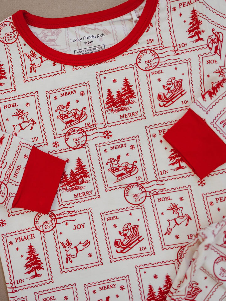 Close up of the North Pole Stamps pajama top showing the red neckline, sleeve cuffs and Christmas stamp
illustrations.