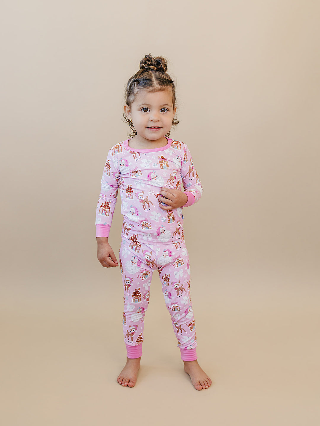 Toddler posing with one foot to the side in the Pink Christmas pajama set.