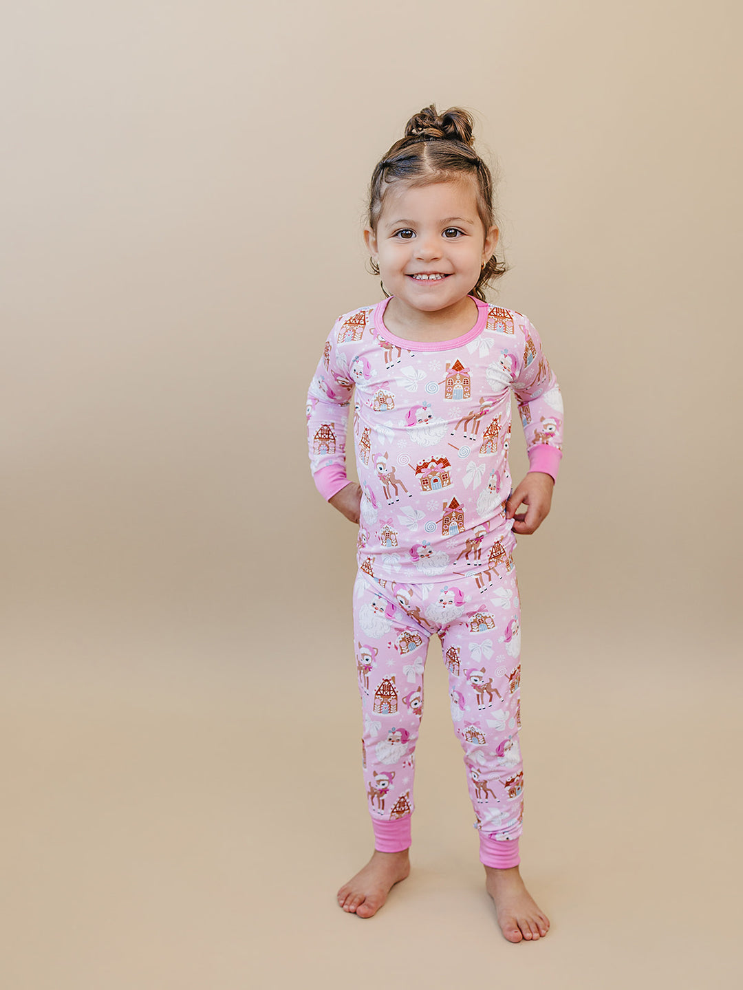 Toddler wearing Pink Christmas two piece pajamas with pink wrist and ankle cuffs.