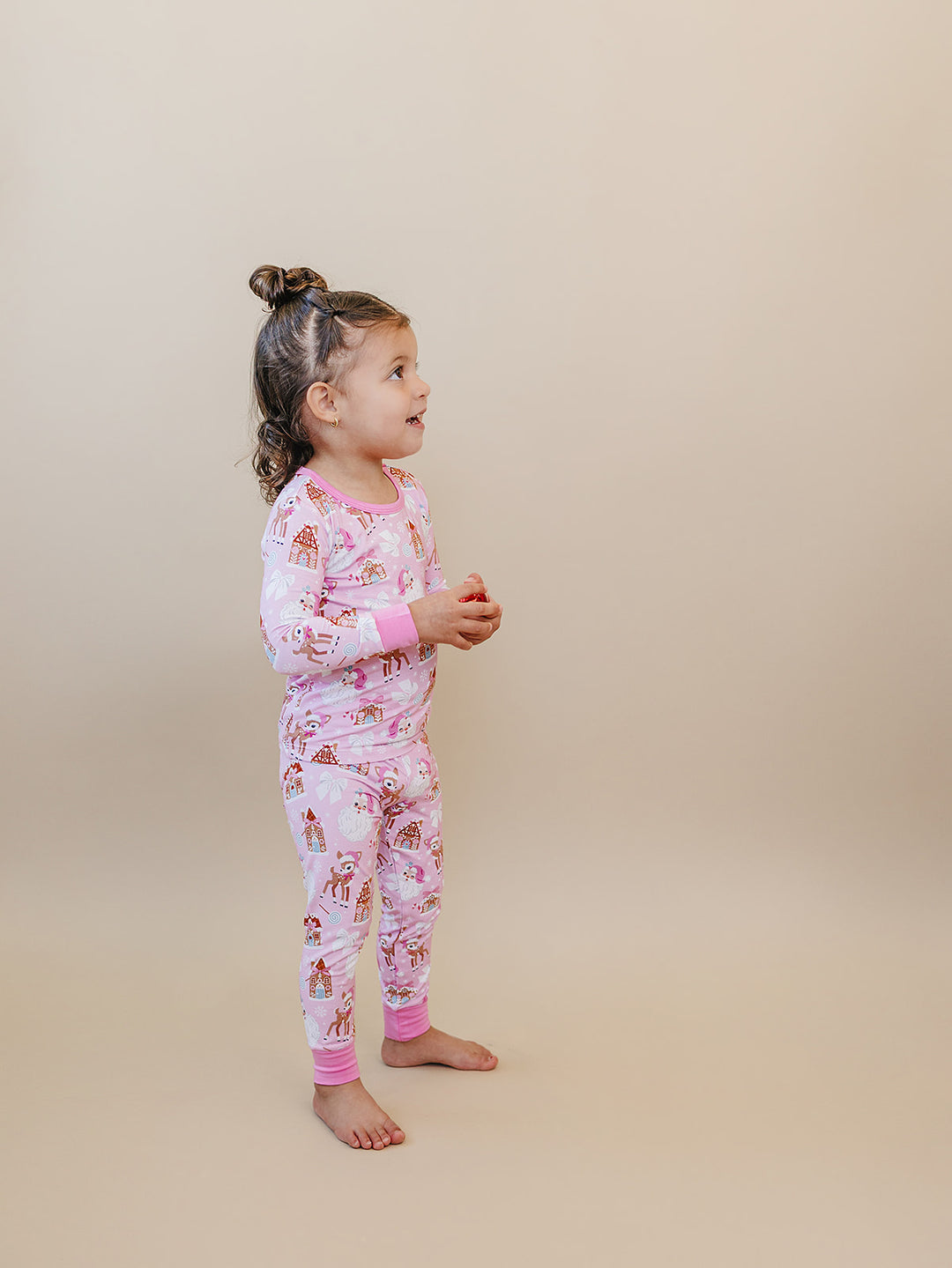 Side view of a toddler wearing the Pink Christmas long sleeve pajama top and matching pants.