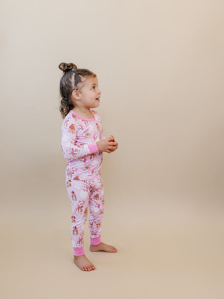 Side view of a toddler wearing the Pink Christmas long sleeve pajama top and matching pants.