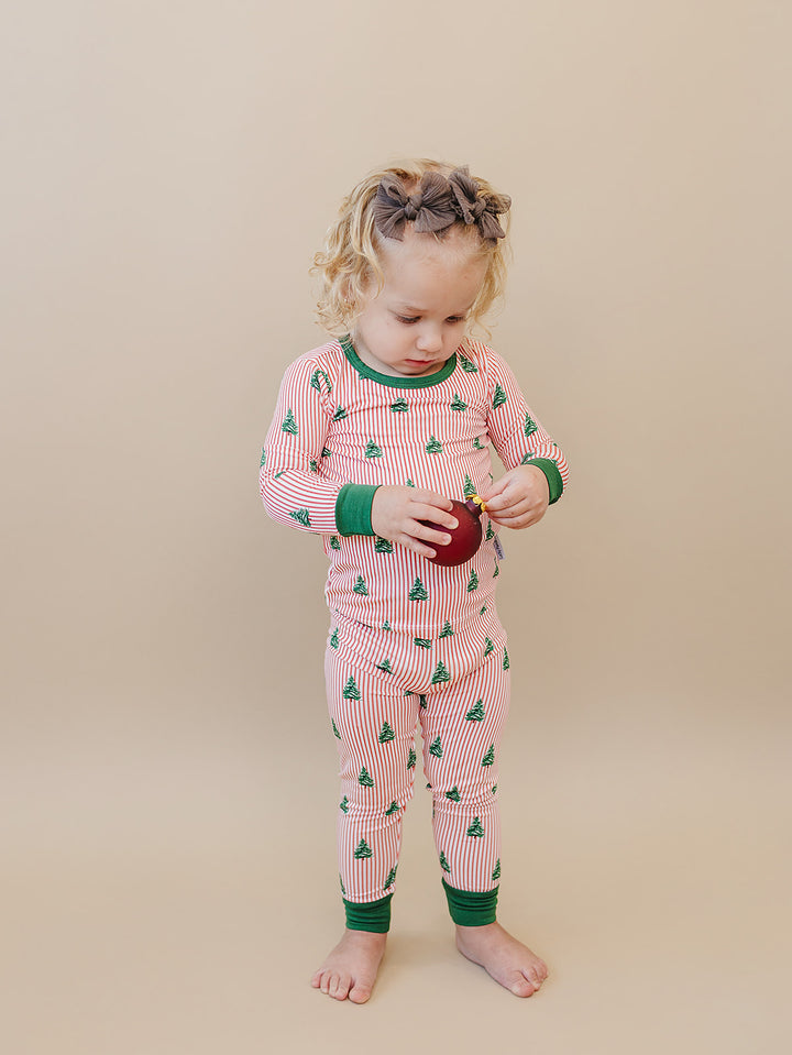Toddler looking down while wearing Magical Trees Christmas pajamas with green ankle cuffs.