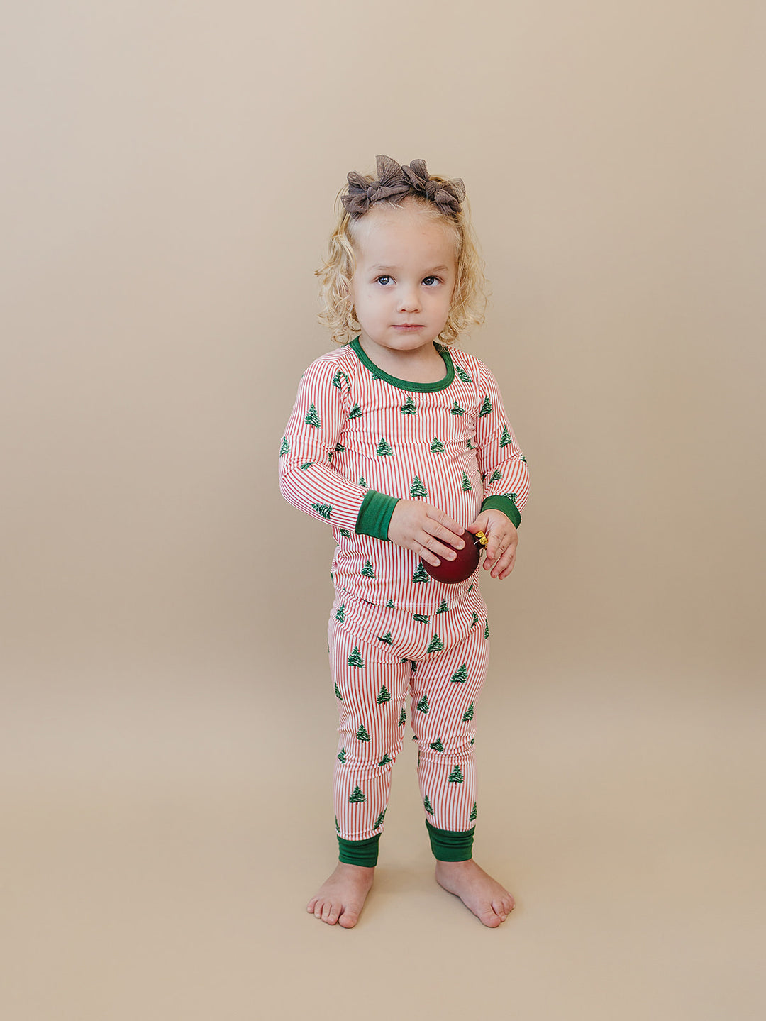 Front view of a toddler wearing the Magical Trees Christmas pajama set with matching printed pants.