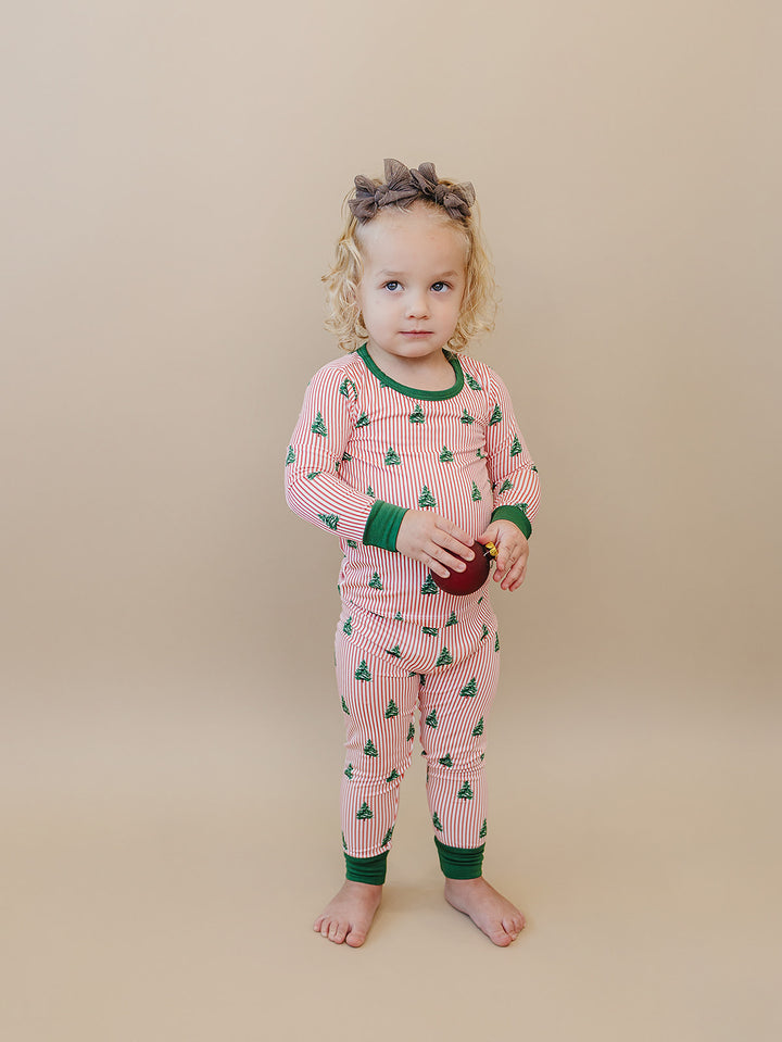 Front view of a toddler wearing the Magical Trees Christmas pajama set with matching printed pants.