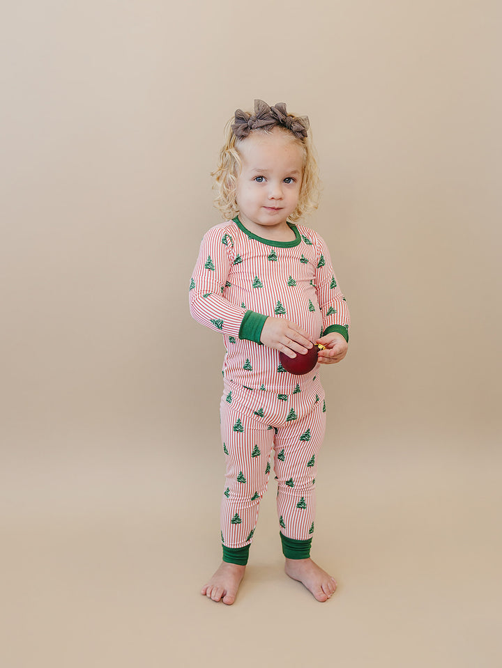 Toddler standing barefoot in the Magical Trees long sleeve pajama top and matching striped pants.