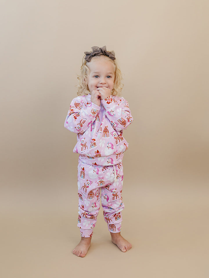 Front view of a toddler in the Pink Christmas jogger set with hands raised near their face.
