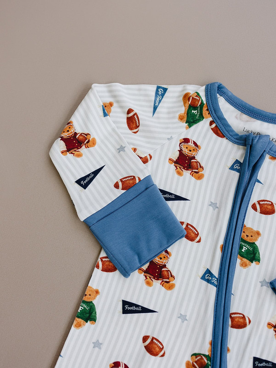 Close-up flat lay of the Touchdown Teddy bamboo romper and dusty blue zipper trim.