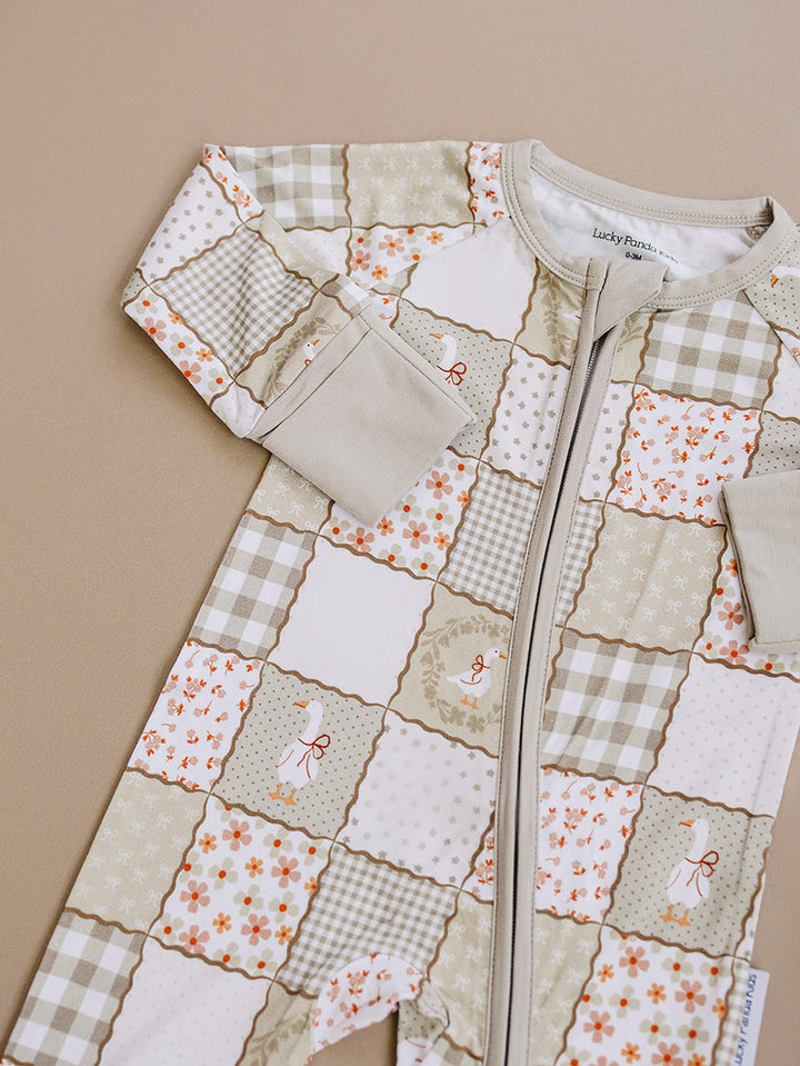 Close-up product detail of the Cottage Goose bamboo romper, showing the patchwork print, zipper, and fabric.
