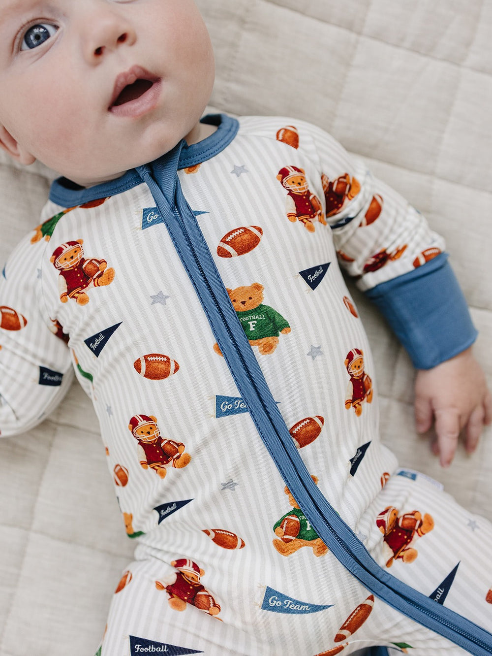 Close-up of a baby wearing the Touchdown Teddy bamboo romper with football and teddy bear print.