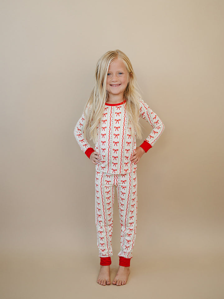 Full length front view of a child wearing Christmas Bows pajamas with hands on hips.