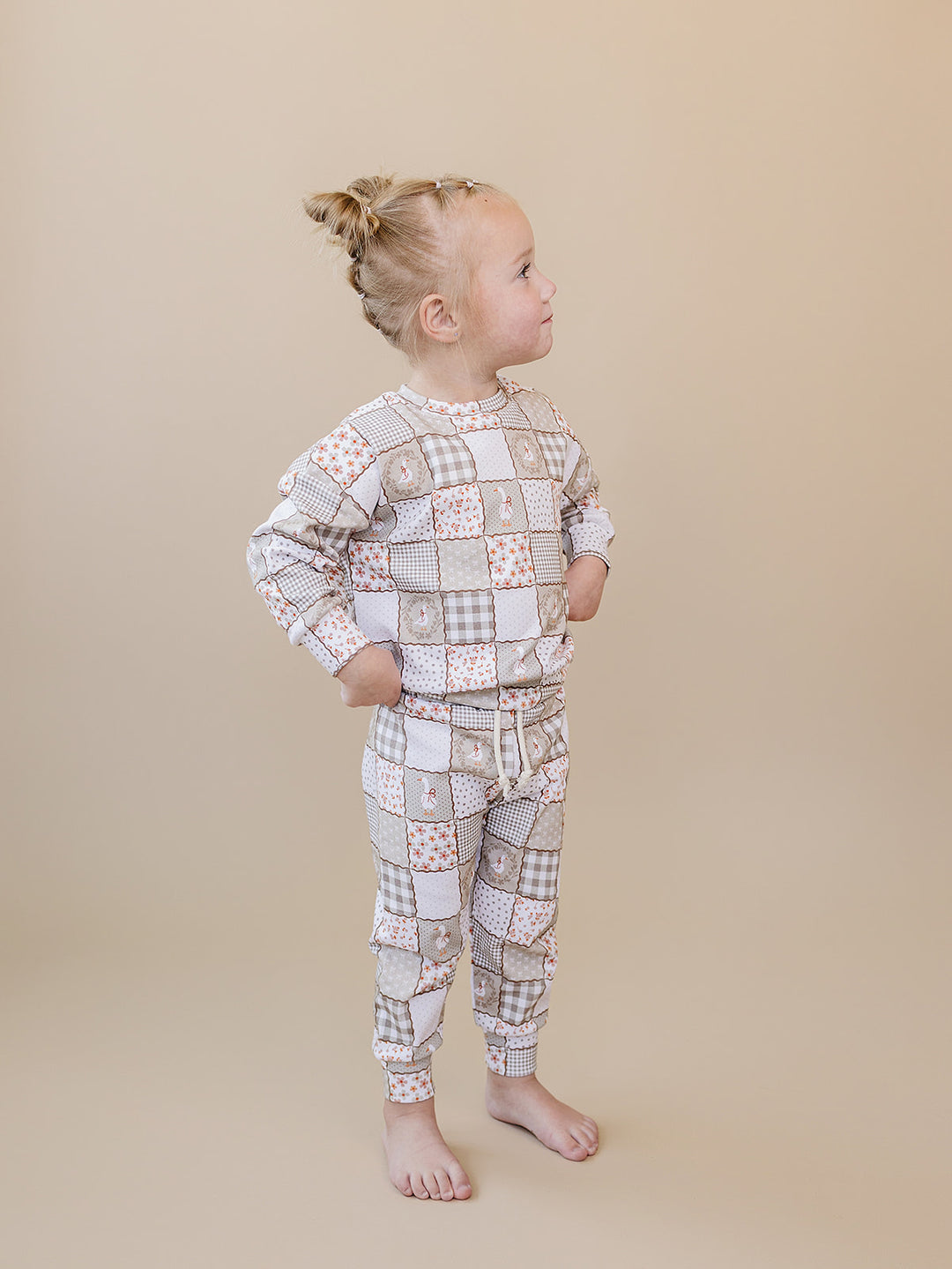 Full-length back view of a toddler girl wearing the Cottage Goose jogger set against a beige background.