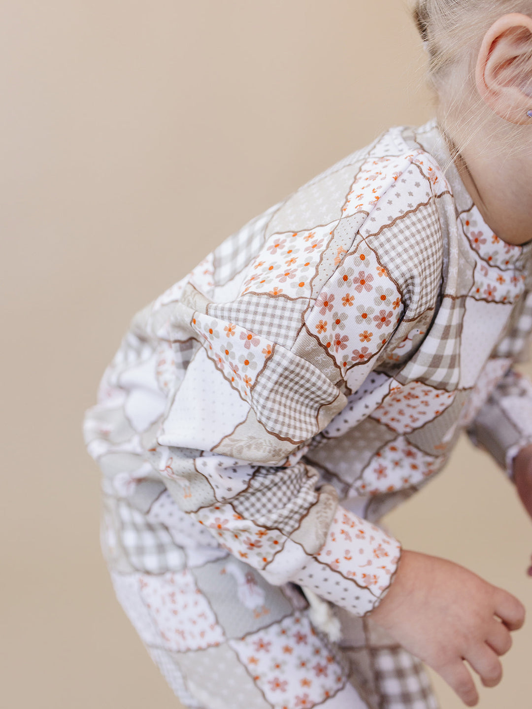 Close-up of a toddler crouching in the Cottage Goose jogger set, showing the flexible fit and patchwork print.