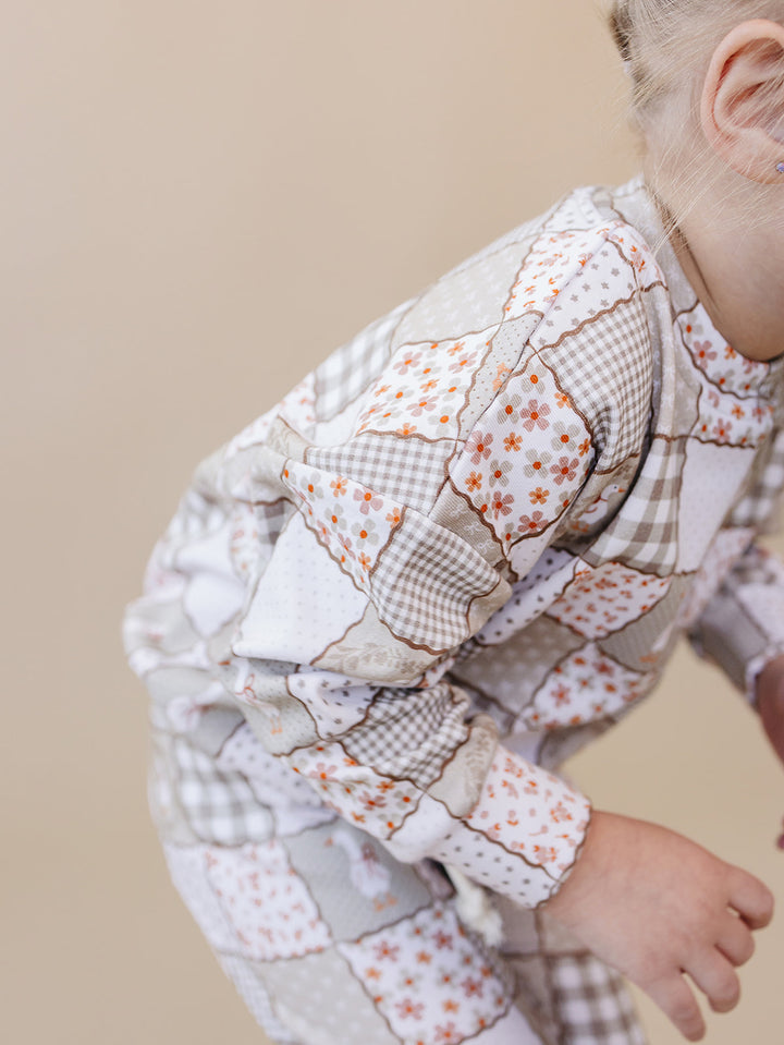 Close-up of a toddler crouching in the Cottage Goose jogger set, showing the flexible fit and patchwork print.