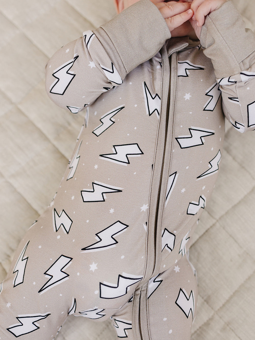 Close-up product detail of the Latte Bolts bamboo romper, showing the zipper and lightning bolt print.