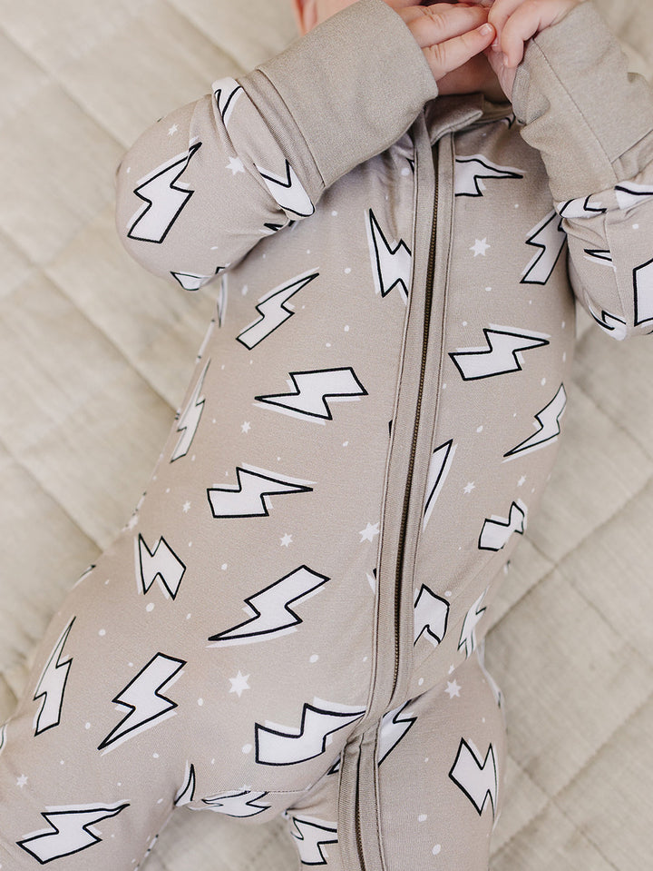Close-up product detail of the Latte Bolts bamboo romper, showing the zipper and lightning bolt print.