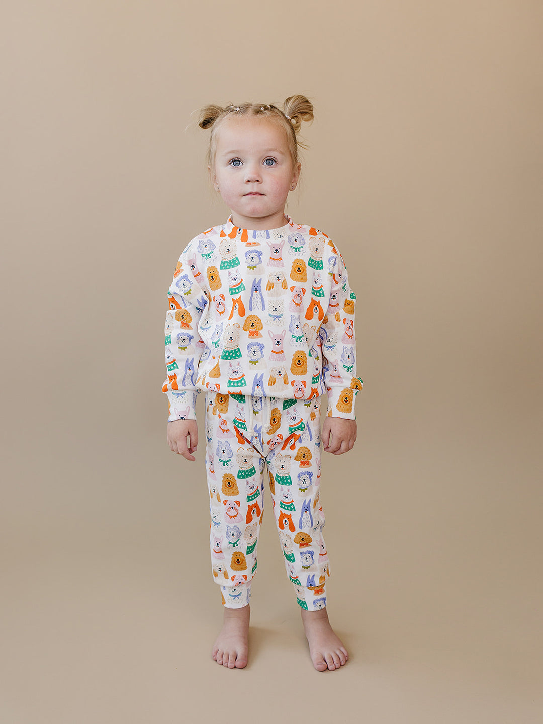 Toddler standing in the Puppy Club cotton long-sleeve top and matching dog-print jogger pants.