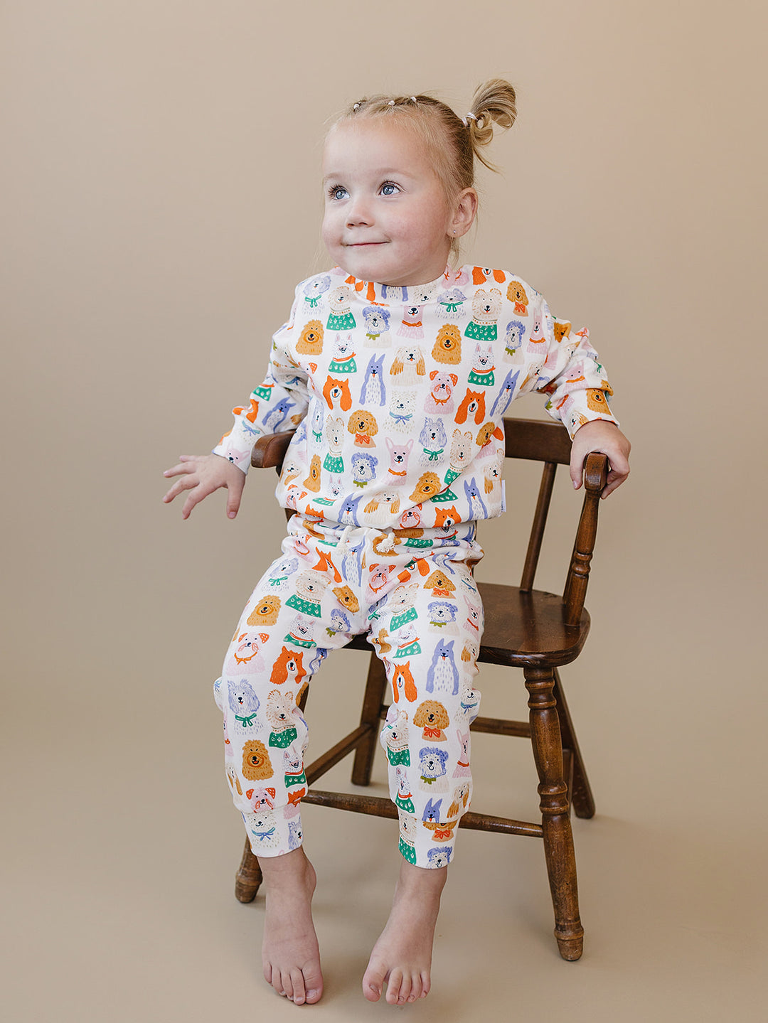 Toddler seated on a wooden chair in the Puppy Club cotton top and matching joggers.