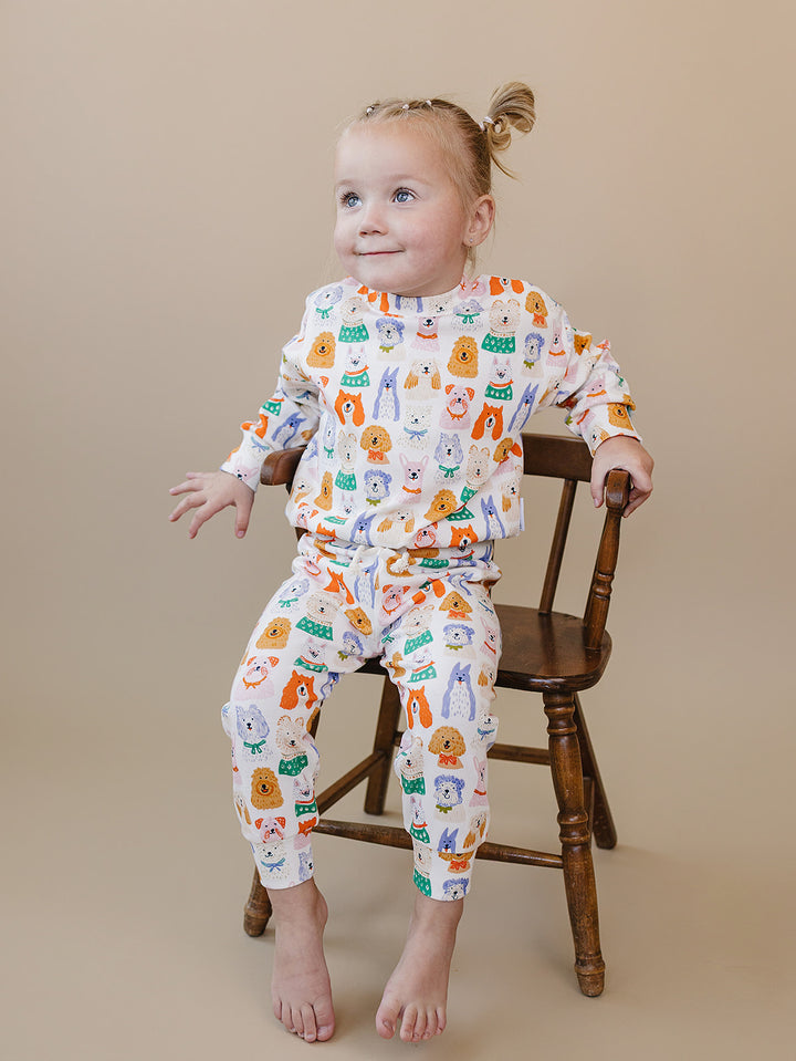 Toddler seated on a wooden chair in the Puppy Club cotton top and matching joggers.
