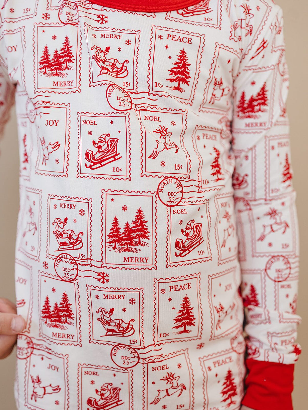 Detail of the North Pole Stamps pajama top showing red Christmas postage stamp illustrations and a red sleeve cuff.