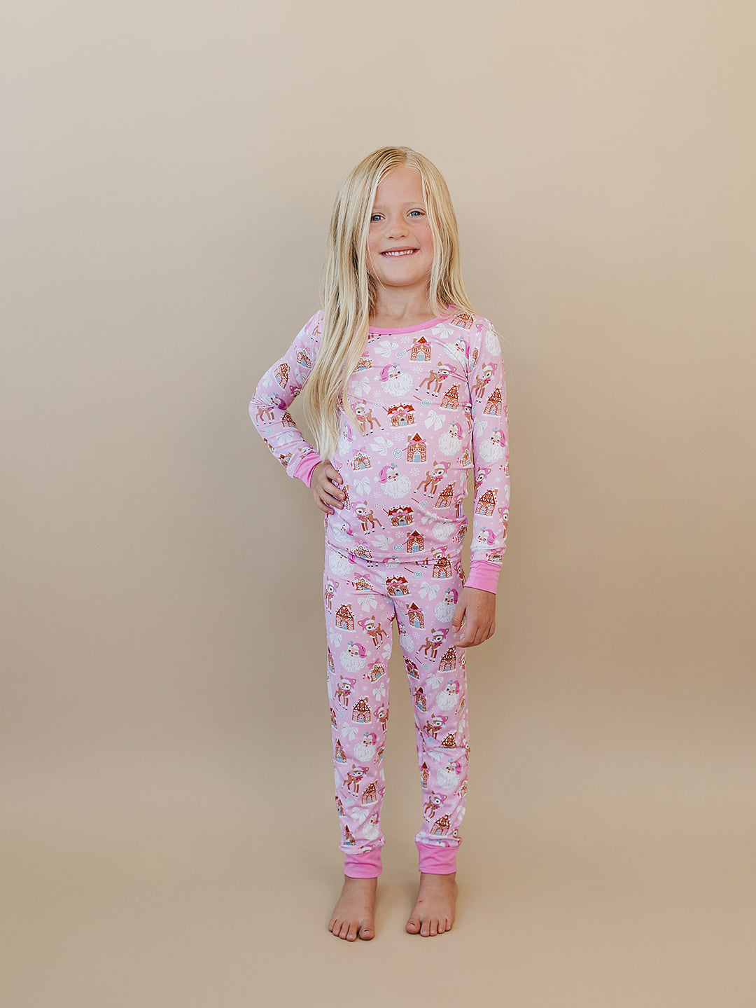 Child standing in the Pink Christmas long sleeve pajama top and matching printed pants.