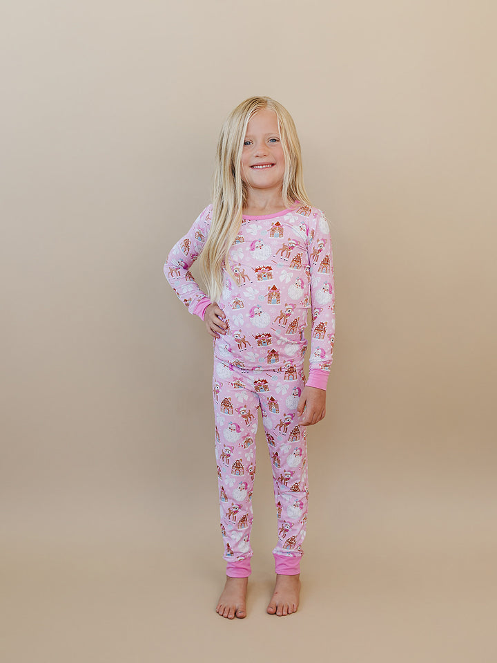 Child standing in the Pink Christmas long sleeve pajama top and matching printed pants.