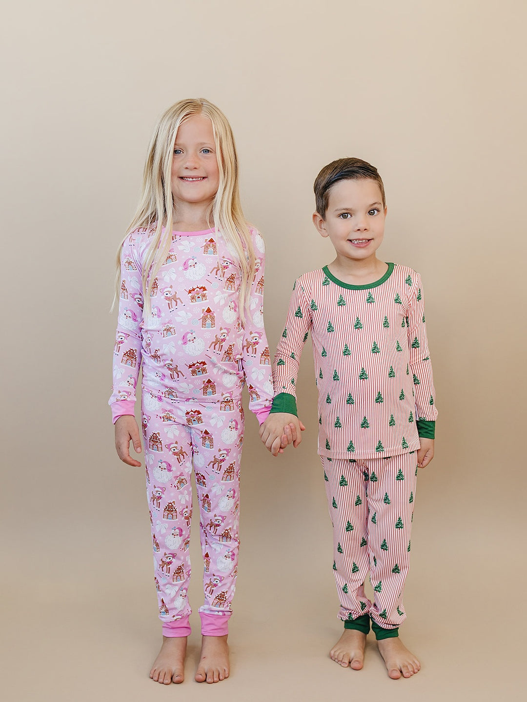 Children side by side wearing Pink Christmas pajamas with pink trim and Magical Trees pajamas with green trim.