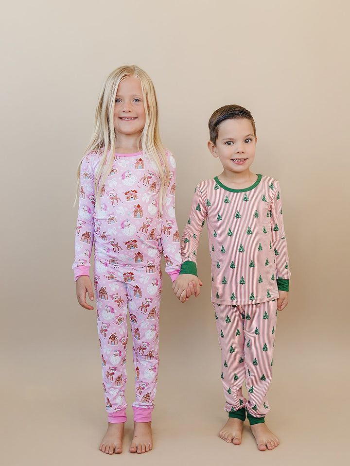 Children side by side wearing Pink Christmas pajamas with pink trim and Magical Trees pajamas with green trim.