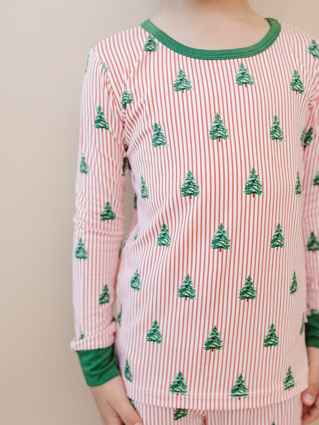 Close up of the Magical Trees pajama top with green Christmas trees, red and white stripes and green trim.