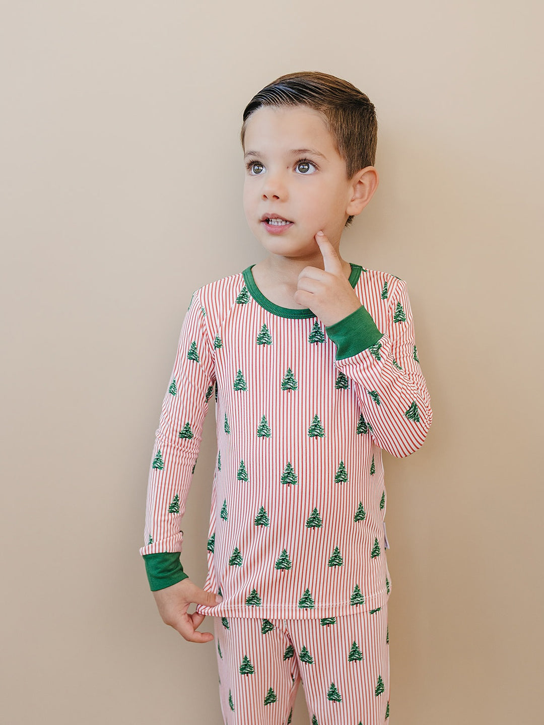 Child looking to the side in the Magical Trees Christmas pajama top with a green neckline.
