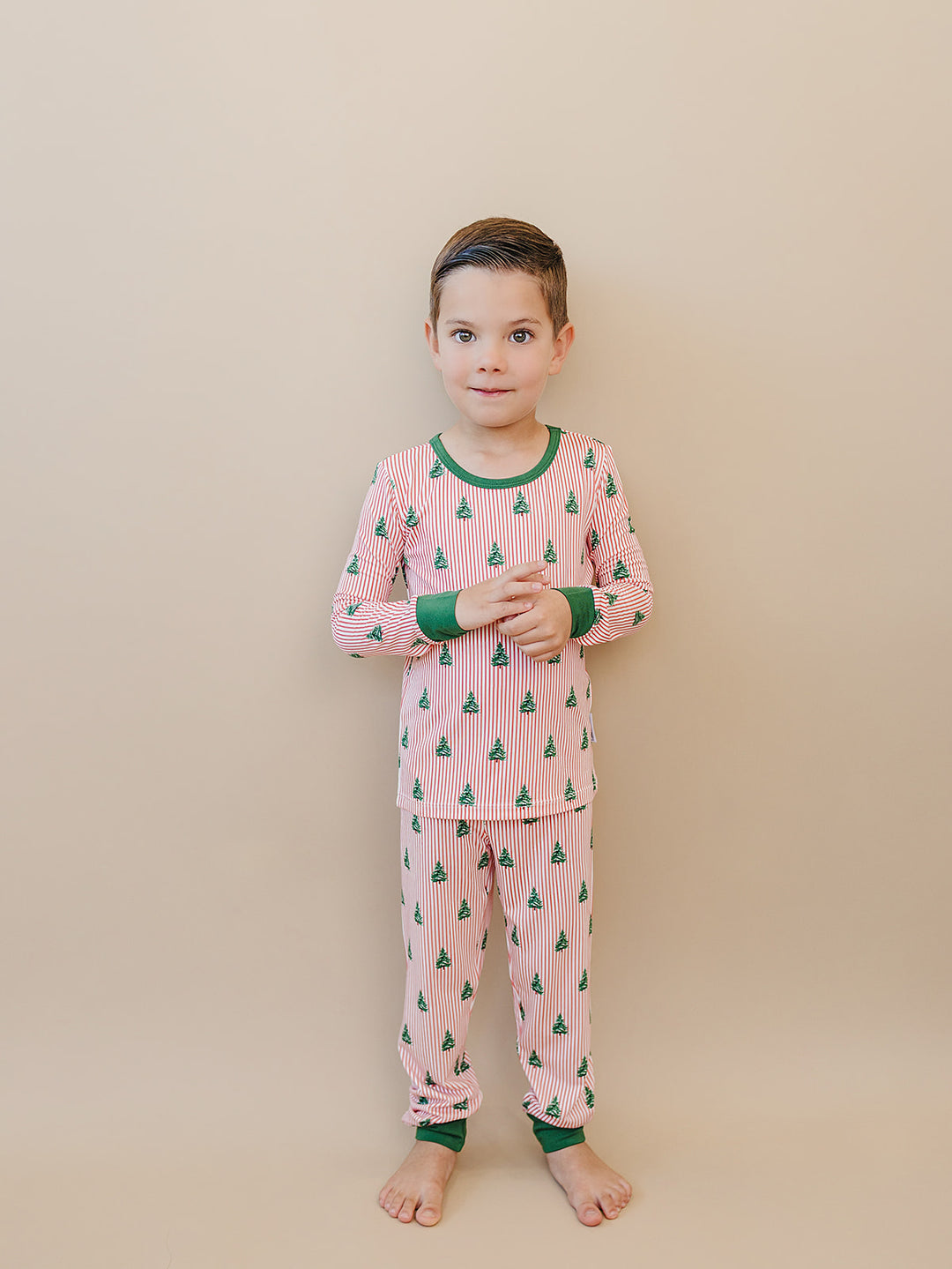 Child wearing Magical Trees two piece pajamas with hands held together in front.