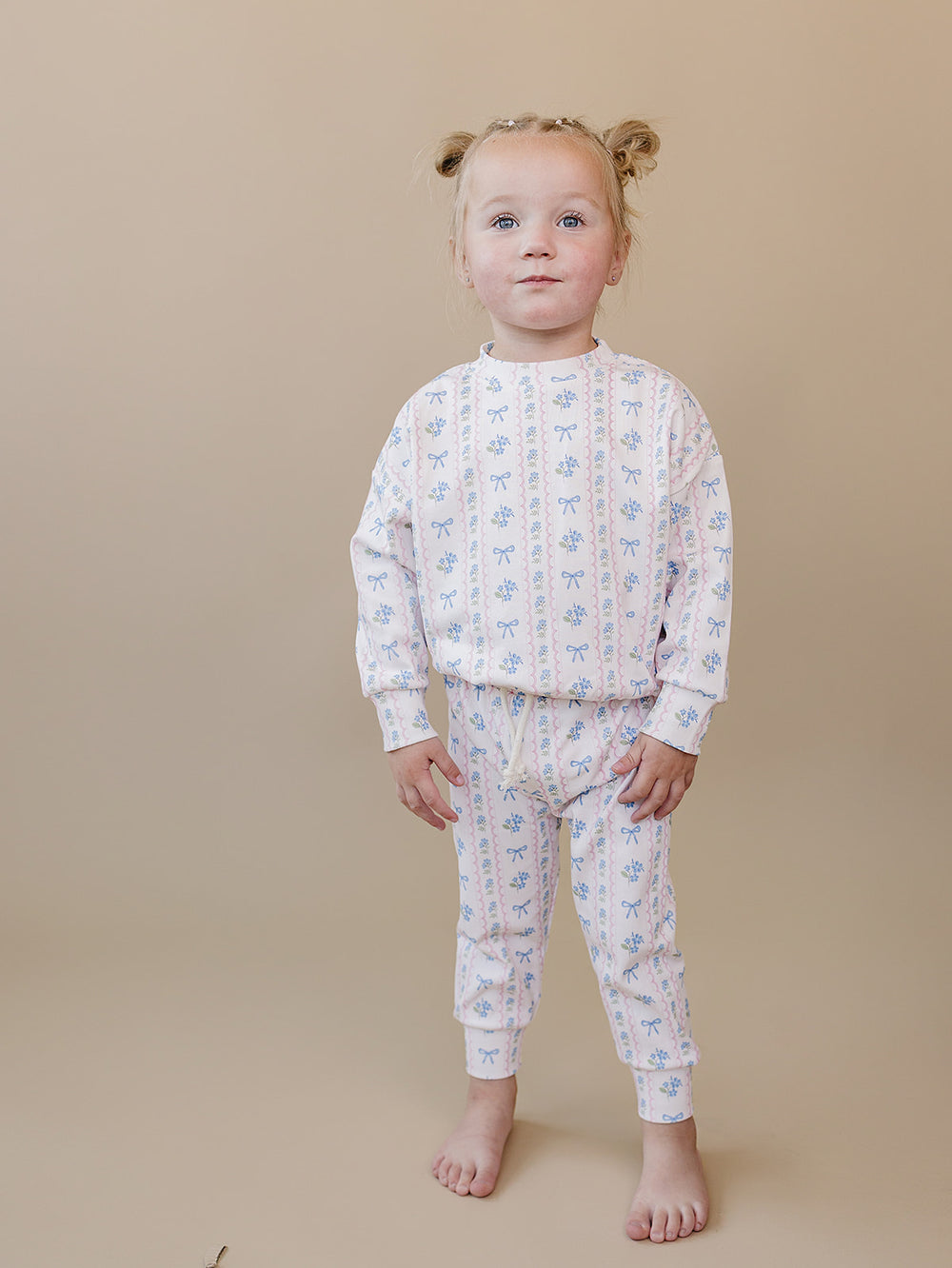 Toddler standing in the Whimsy Bloom floral cotton top and matching jogger pants.
