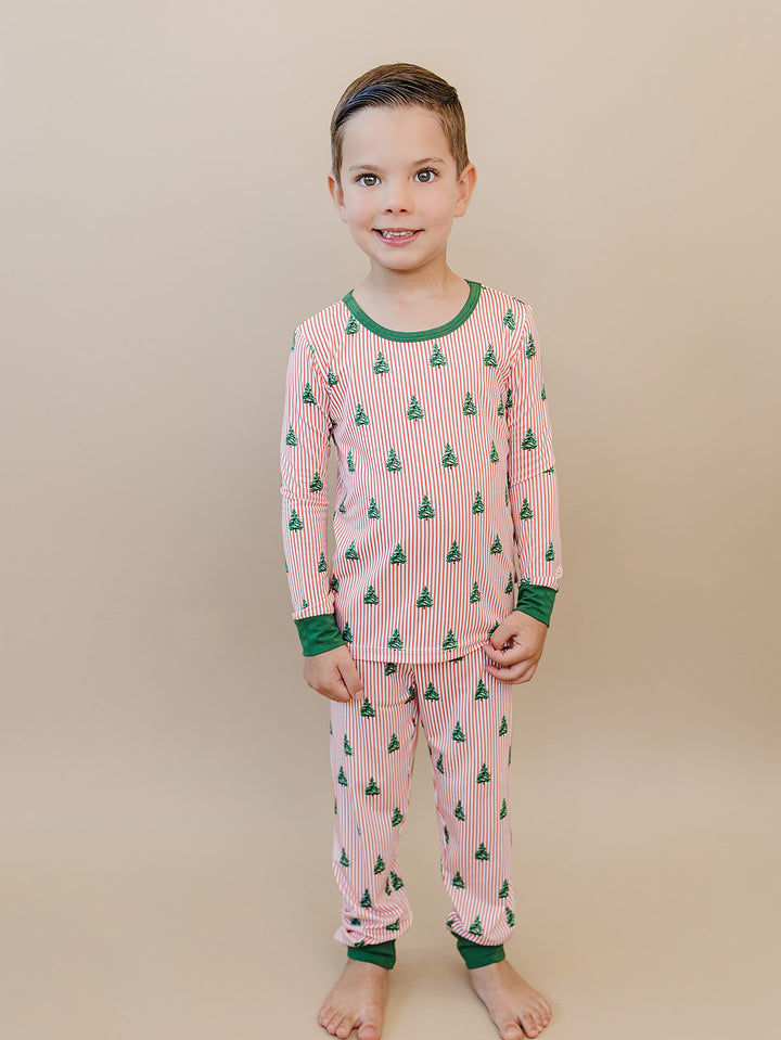 Front view of a child wearing the complete Magical Trees Christmas pajama set with green trim.