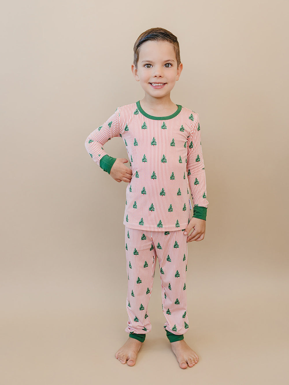 Child standing in Magical Trees two piece Christmas pajamas with a long sleeve top and matching pants.