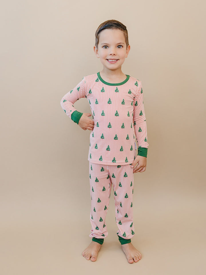 Child standing in Magical Trees two piece Christmas pajamas with a long sleeve top and matching pants.