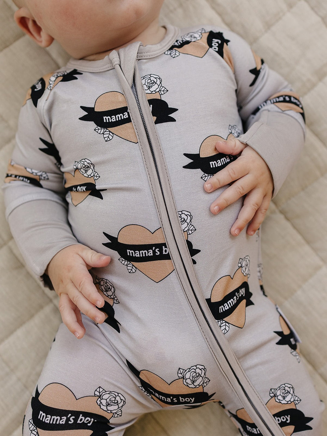 Close-up of the front zipper and heart-and-banner print on the Mama’s Boy bamboo romper.