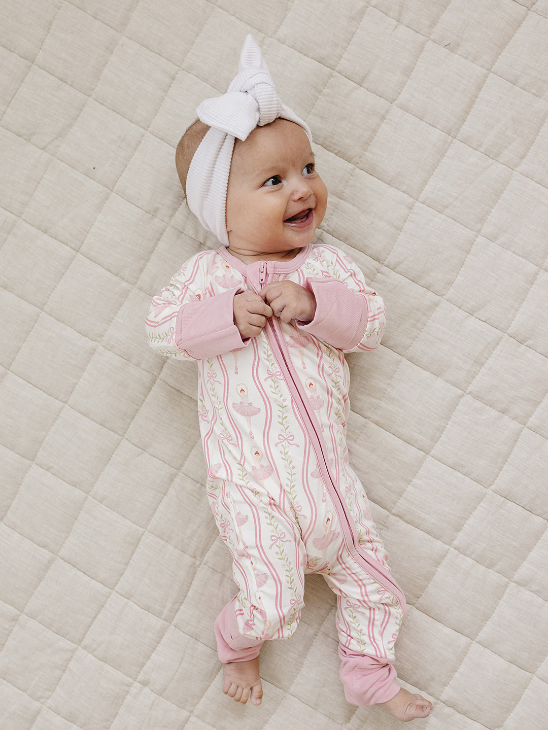Baby wearing the Little Ballerina ballerina-print bamboo romper and white bow headband.