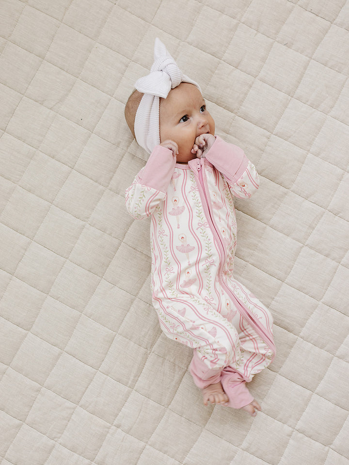 Side view of a baby wearing the Little Ballerina bamboo romper with convertible footies.