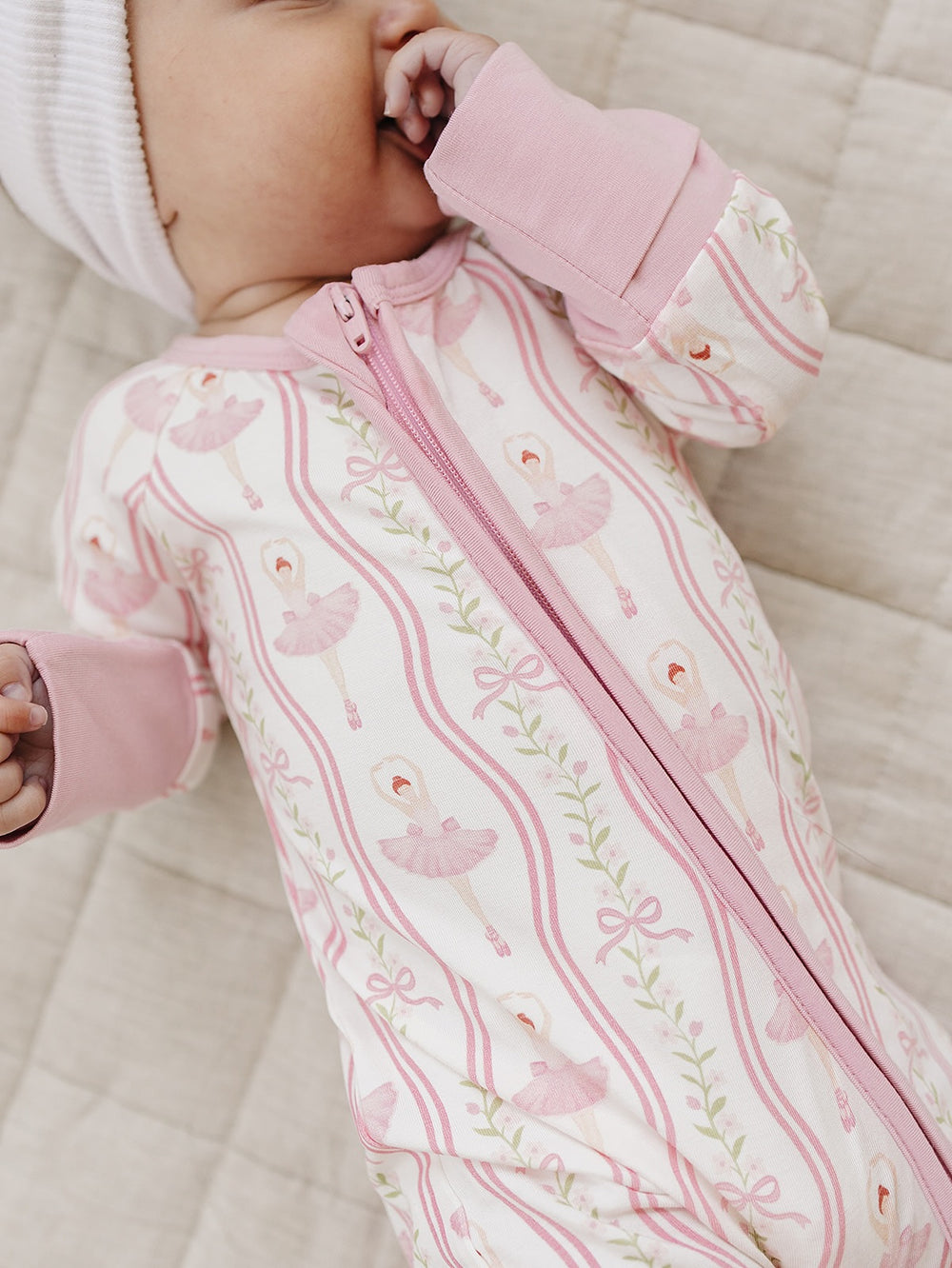 Close-up of a baby wearing the pink Little Ballerina bamboo romper with a two-way zipper.