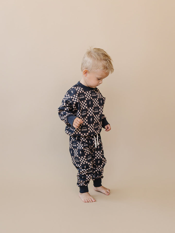 Side view of a toddler wearing the Long Live Boyhood cotton jogger set against a beige background.