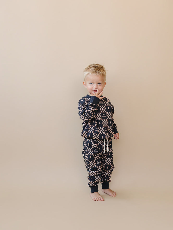 Toddler with one hand near their face wearing the Long Live Boyhood cotton jogger set.