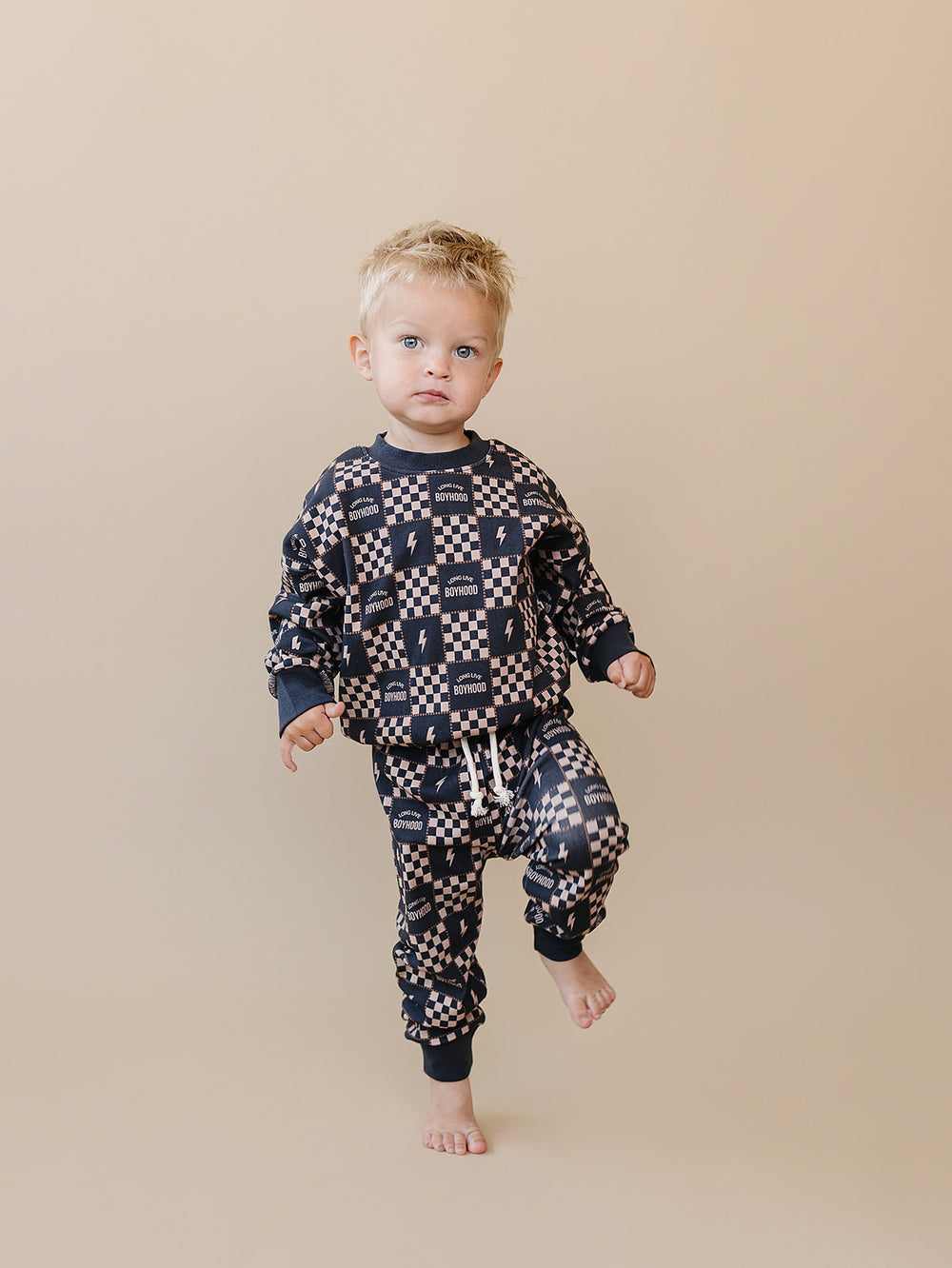 Toddler stepping forward in the Long Live Boyhood lightning bolt-print cotton jogger set.