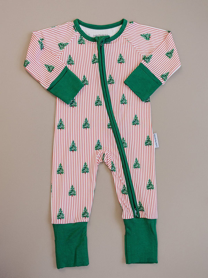 Magical Trees zip romper laid flat, showing Christmas trees over red and white stripes with green trim.