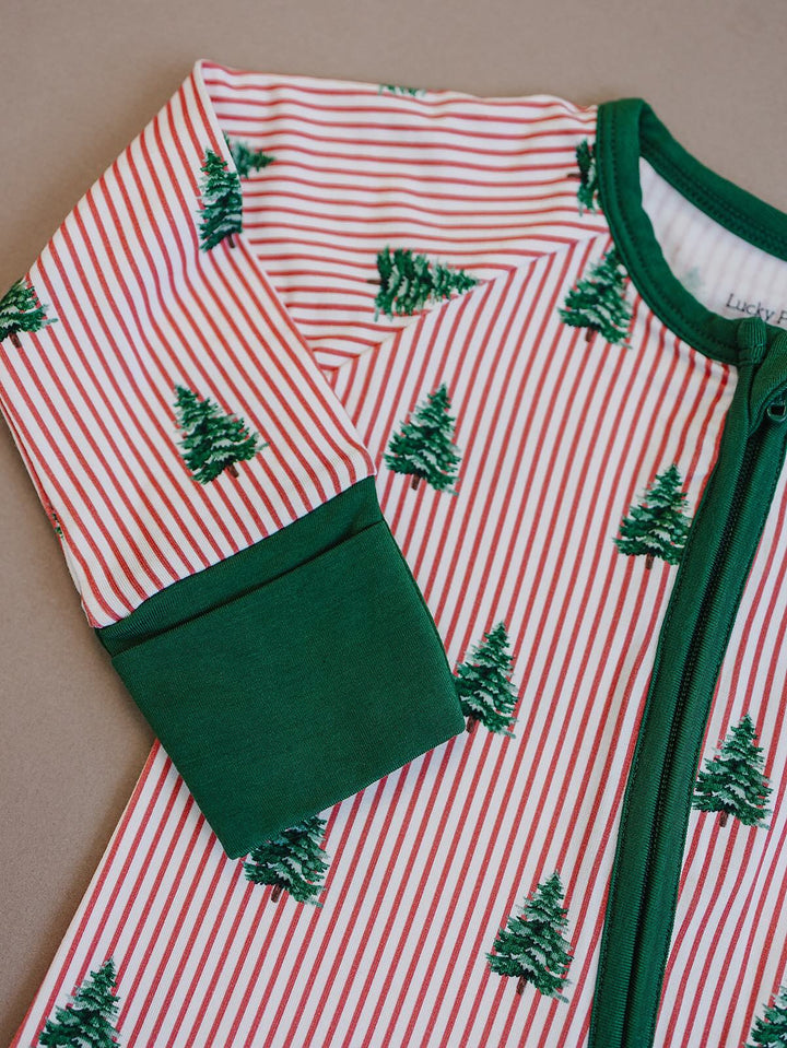Close up of the Magical Trees romper showing striped fabric, green Christmas trees, zipper and sleeve cuff.