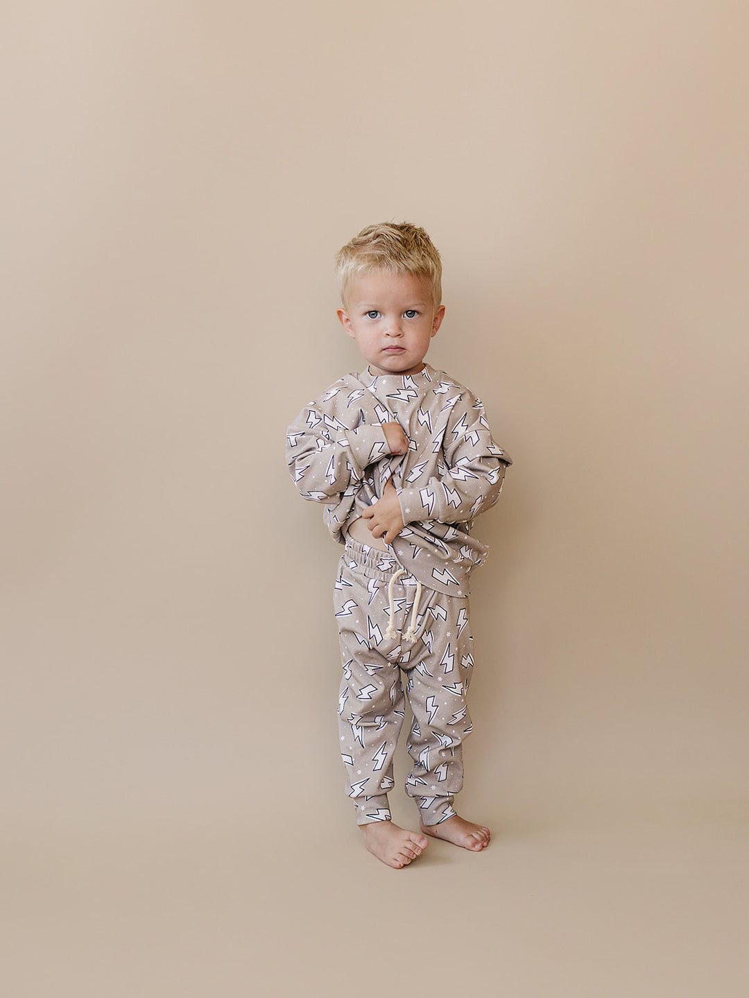 Toddler boy modeling the Latte Bolts jogger set in a full-length front studio view.