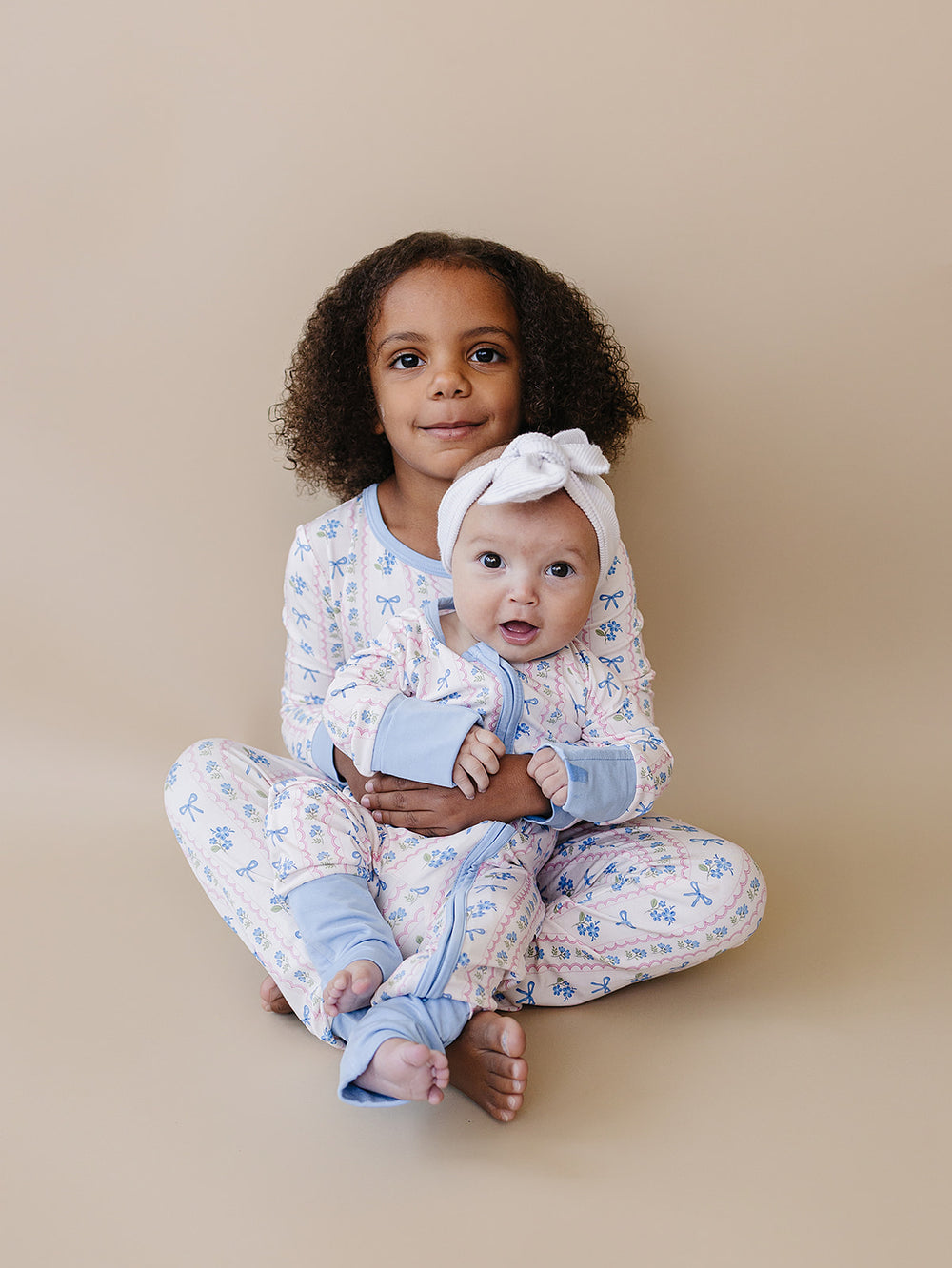 Child wearing the Whimsy Bloom bamboo two-piece set with pastel flowers, blue bows, and light blue trim.