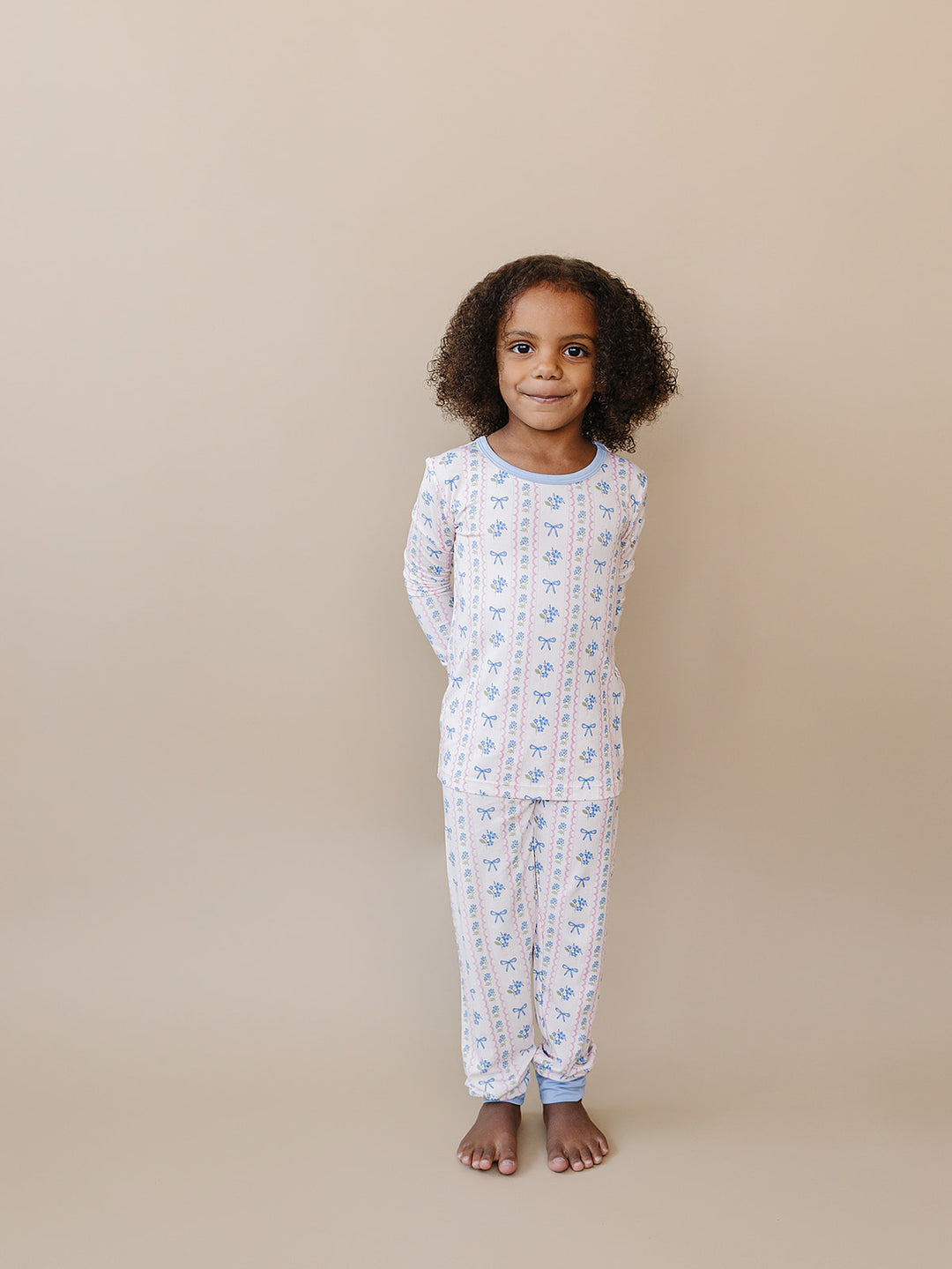 Child standing with hands behind their back in the Whimsy Bloom bamboo top and matching pants.
