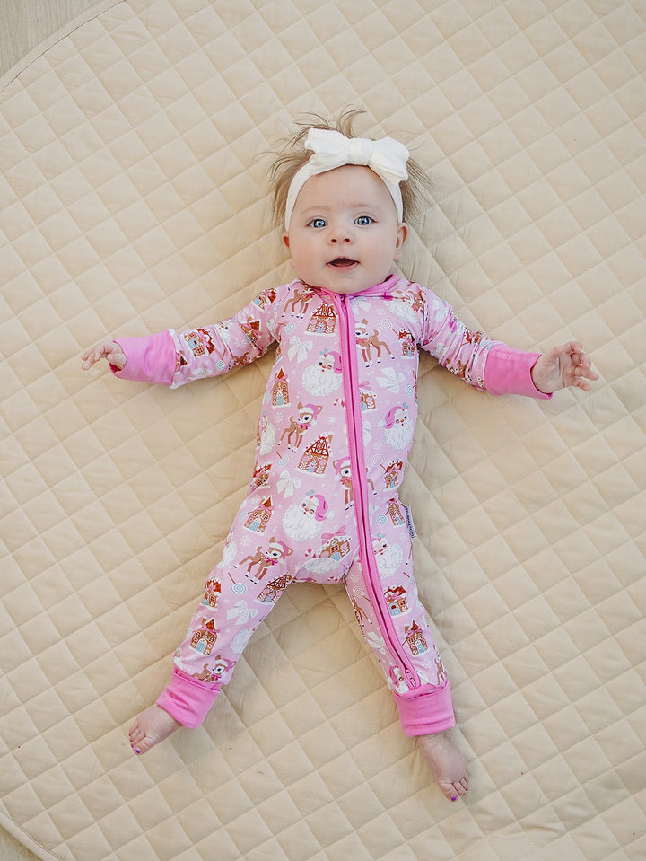 Baby lying with arms out in the Pink Christmas romper, showing the holiday print and pink cuffs.