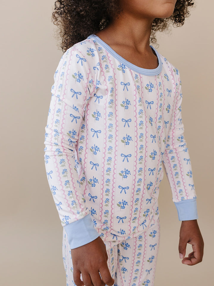 Close-up side view of the Whimsy Bloom bamboo top, showing the floral print and light blue cuffs.